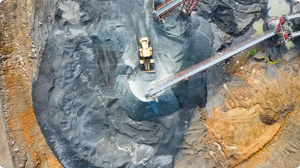 Aerial view of mining equipment in action at a quarry, moving materials for processing.