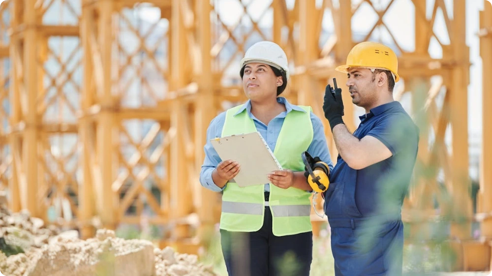Workers discussing safety procedures at a construction site during IOSH training.