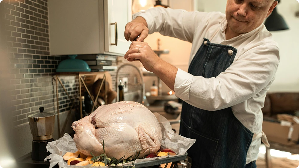 Chef preparing raw turkey in kitchen, highlighting risk of Campylobacter food poisoning from undercooked poultry