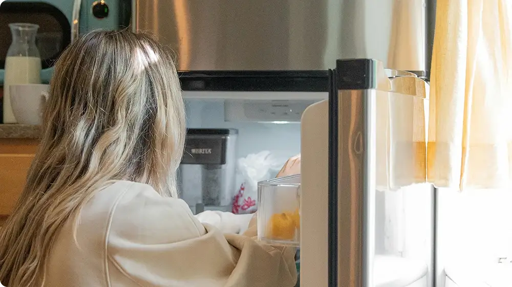 A woman placing warm food in the fridge a common practice that raises food safety concerns.