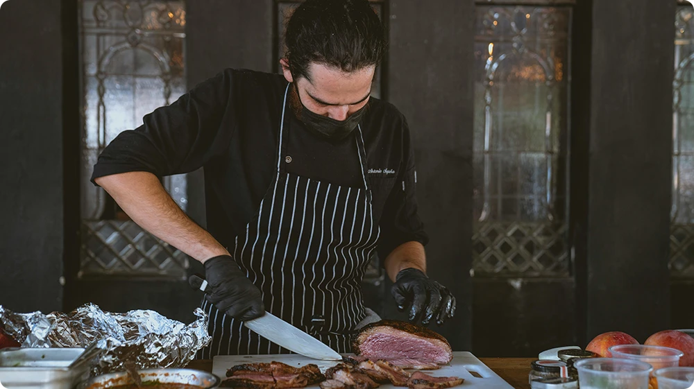 Chef cutting raw beef slices on a clean chopping board to store the beef in the freezer