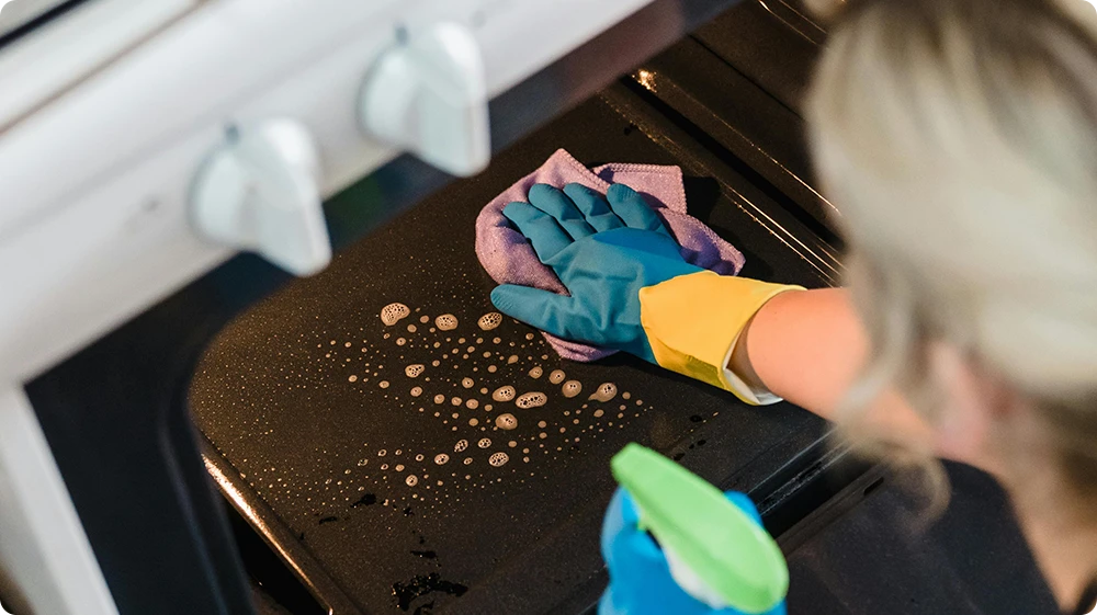 Chef wiping down workstation as part of Clean As You Go policy in a professional kitchen