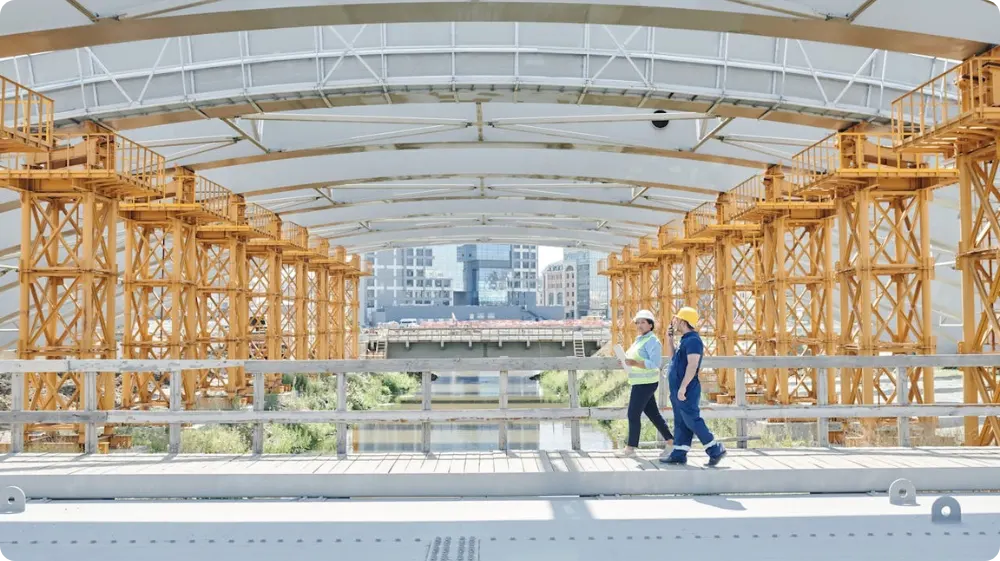 Construction workers in hard hats discussing safety on a bridge project