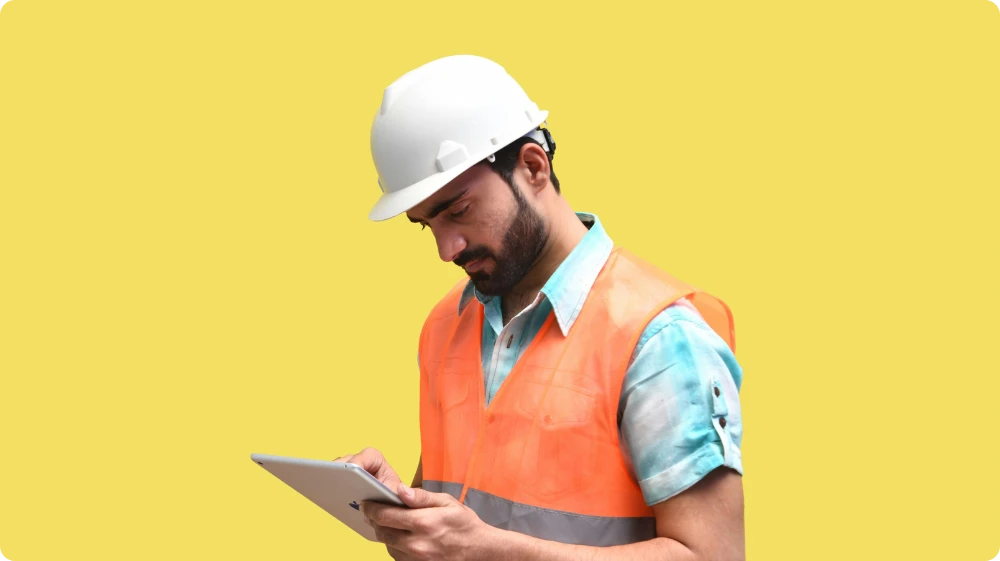 A worker holding a clipboard and reviewing a safety checklist on a construction site.