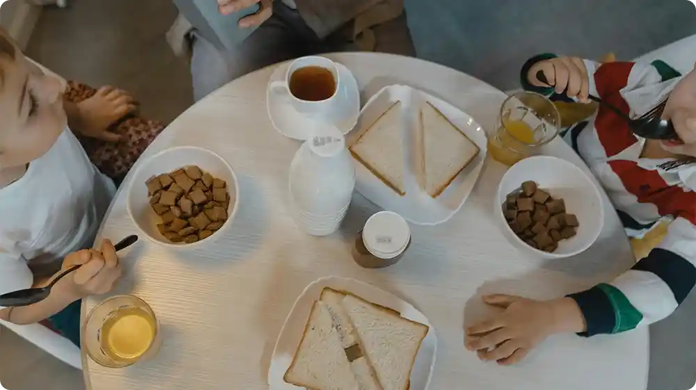 Children eating breakfast with toast, cereal, and juice on table illustrating everyday foods containing additives.