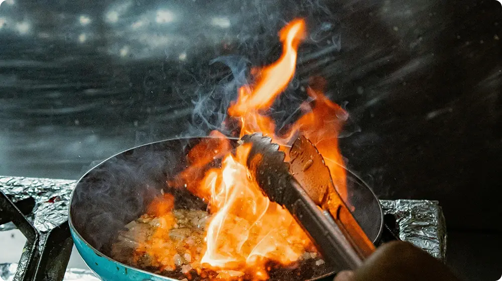 Flaming pan on a gas stove example of a fire hazard in a commercial kitchen