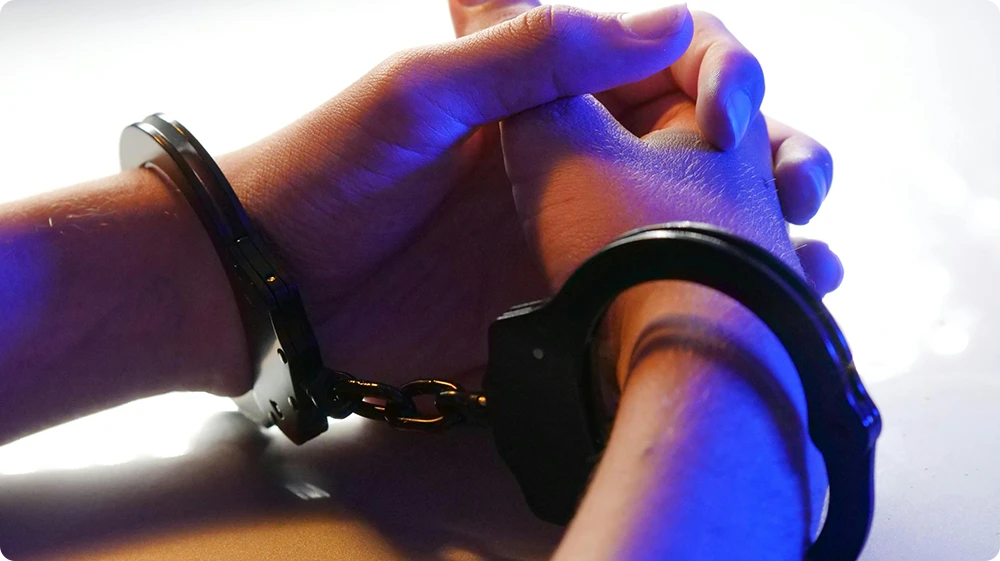 A person in handcuffs representing the legal consequences of breaching the Food Safety Act 1990 in the UK