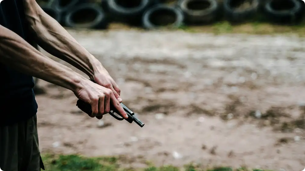 Man holding a gun in an open area, showing the growing risk of gun violence UK