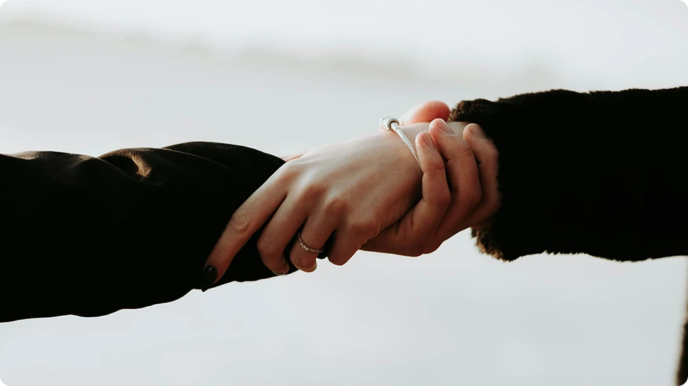 Close-up of a person holding another person's hand to offer comfort during separation anxiety