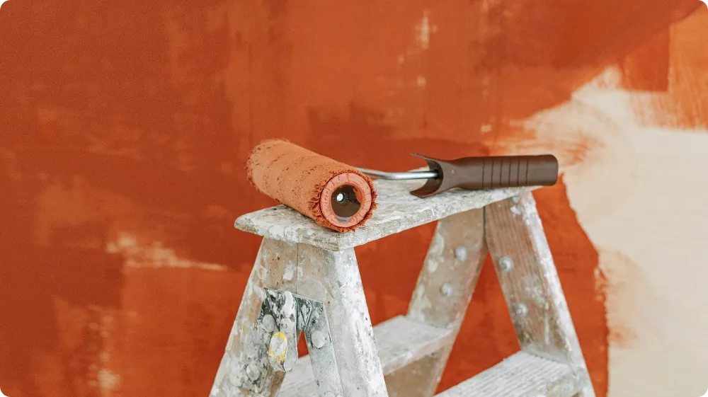 Paint roller placed on ladder decorating tools used in NVQ assessments with Hurak