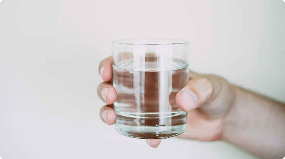 Hand holding a glass of water, symbolising fear of drinking due to hydrophobia
