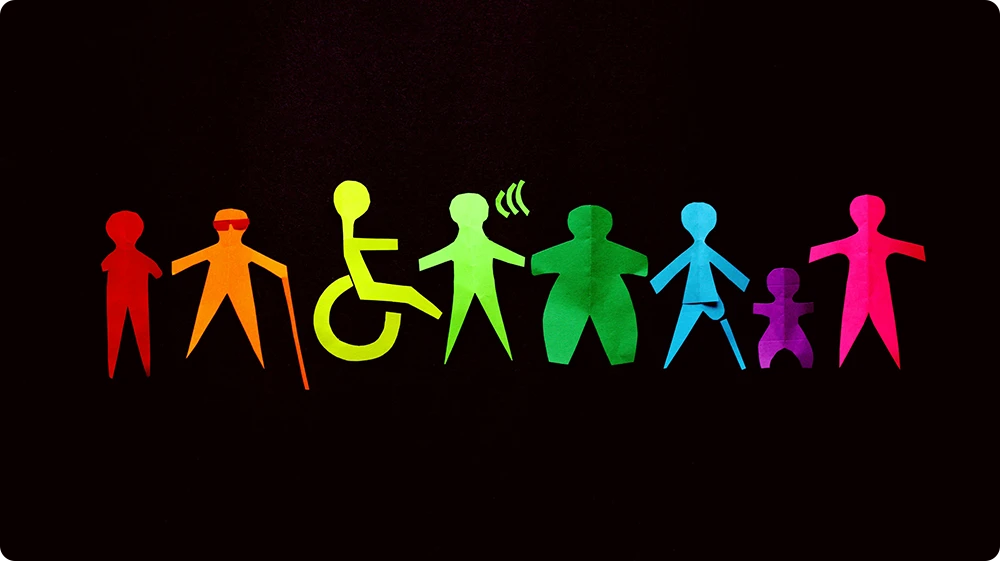 A row of colourful paper cut-out figures on a black background, each representing diversity and inclusion. 
