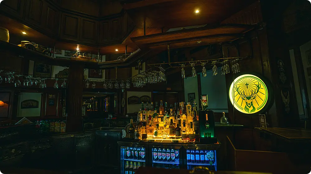 A dimly lit bar interior in a licensed UK venue, featuring liquor on display