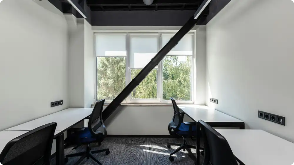 Modern open plan office with desk, chairs, and natural lighting promoting a safe and compliant workplace.