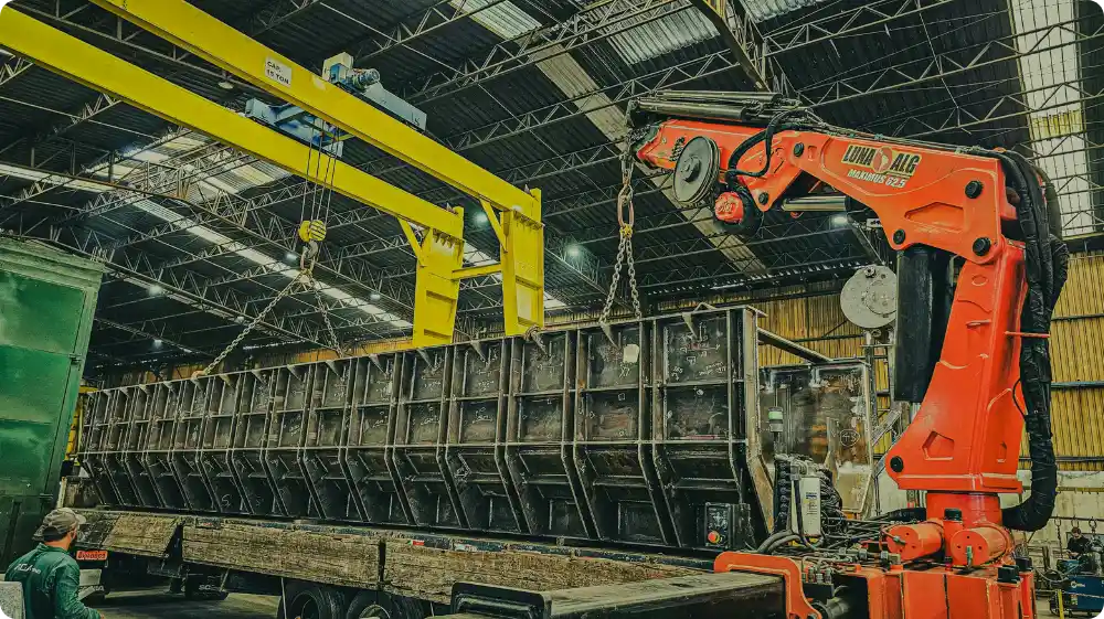 Overhead crane lifting a heavy load onto a truck inside a warehouse