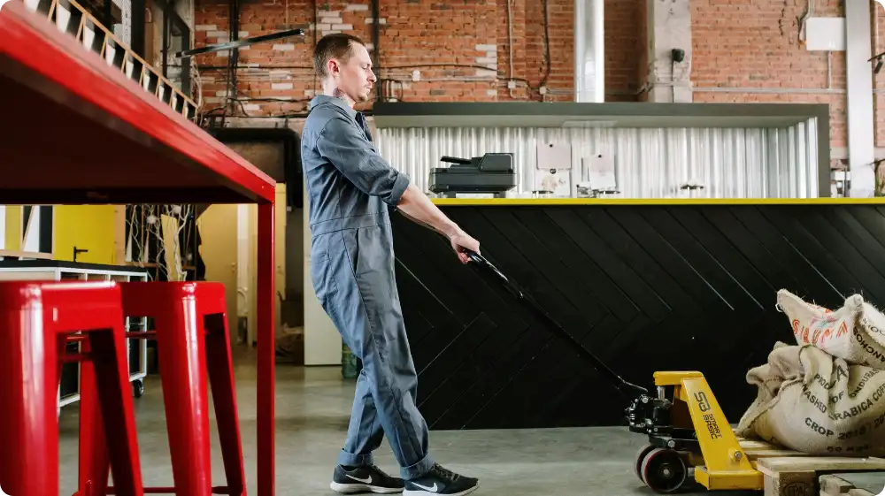 Warehouse worker using a pallet truck to move heavy sacks safely