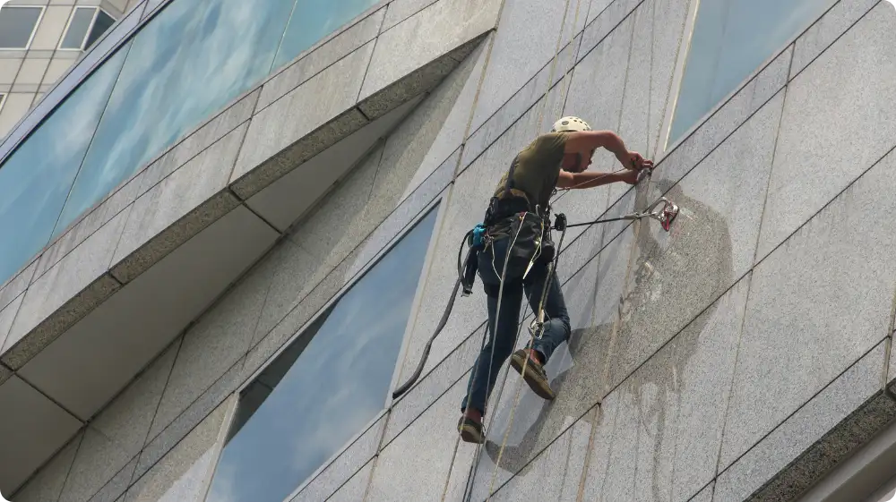 Worker suspended on a rope using a safety harness, demonstrating proper working at height safety protocols to avoid risks.