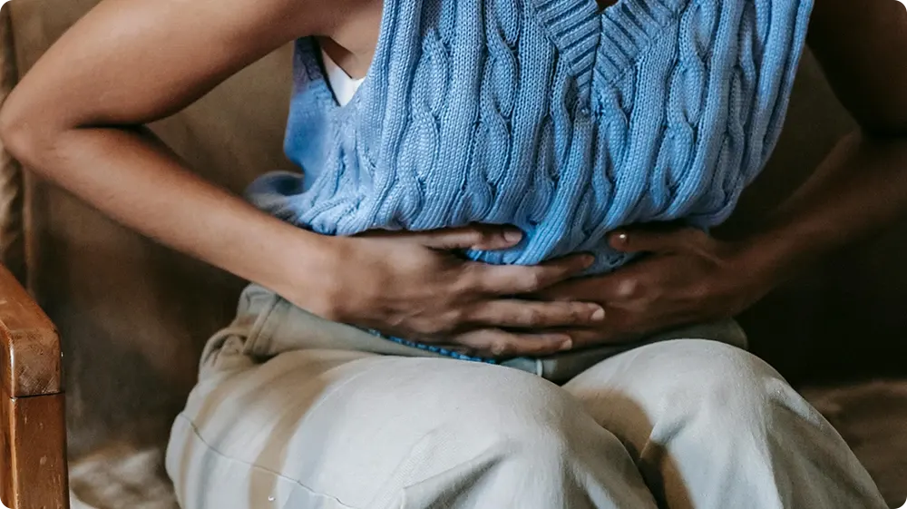 Woman clutching stomach in pain, showing symptoms of ptomaine poisoning or foodborne illness.