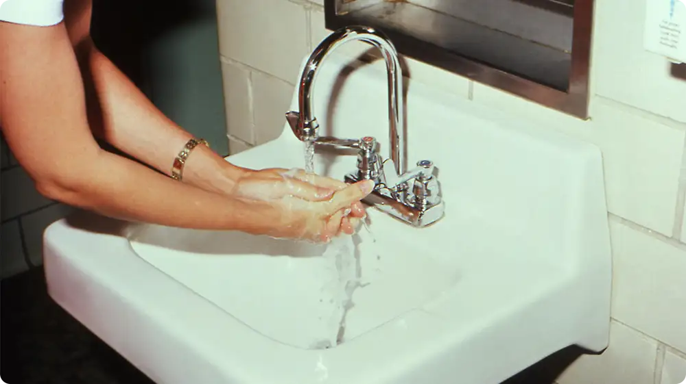 A Person compulsively washing hands as part of obsessive behaviour, a common symptom of OCD contamination.