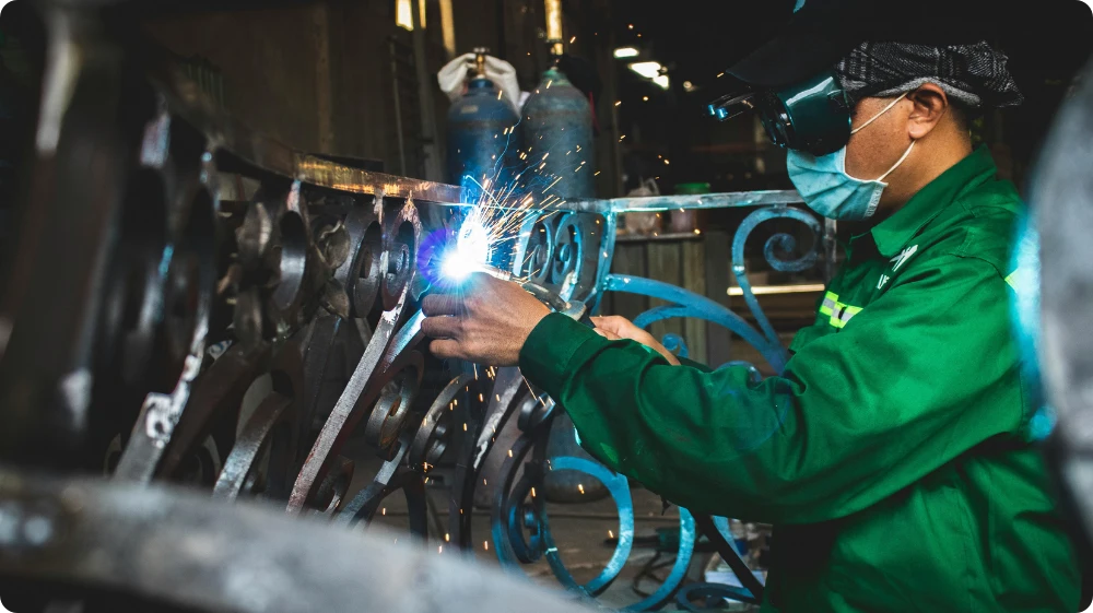 Welder wearing protective equipment while working with metal, highlighting the importance of controlling welding fumes under COSHH regulations in the UK