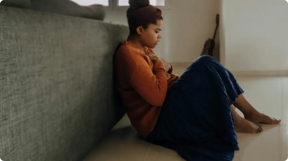 Woman sitting alone on the floor, showing signs of emotional distress or mania episode