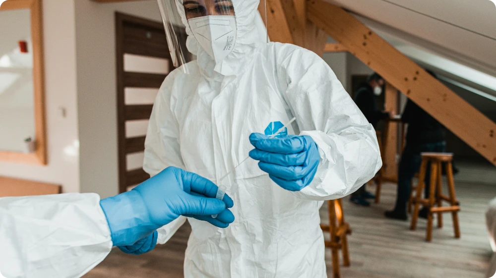 A worker in a protective suit is collecting an asbestos sample during a safety inspection inside a building
