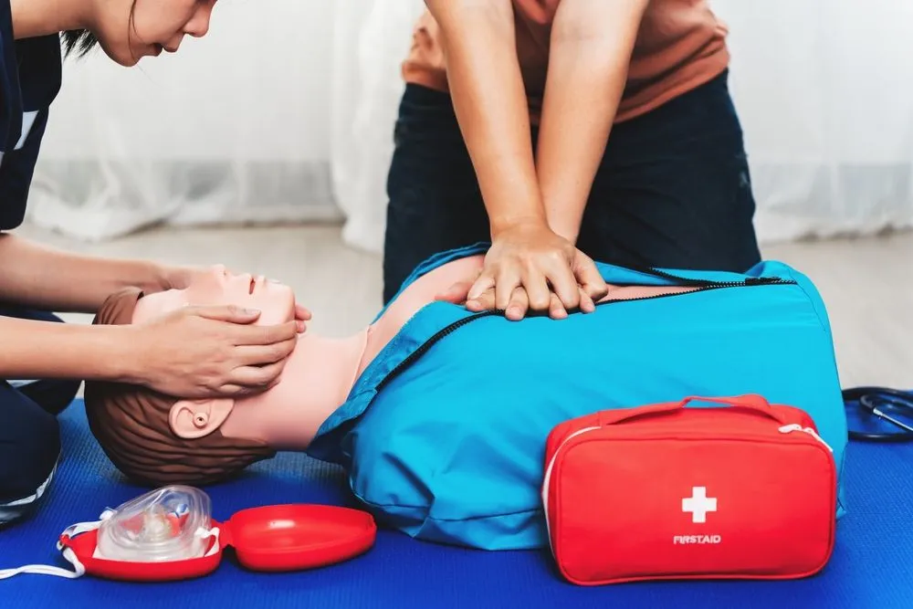CPR training session using a mannequin with a first aid kit in the background
