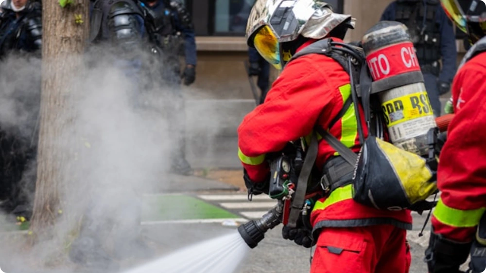 a person using a fire extinguisher to put out a fire, with fire retardant spraying from the nozzle.