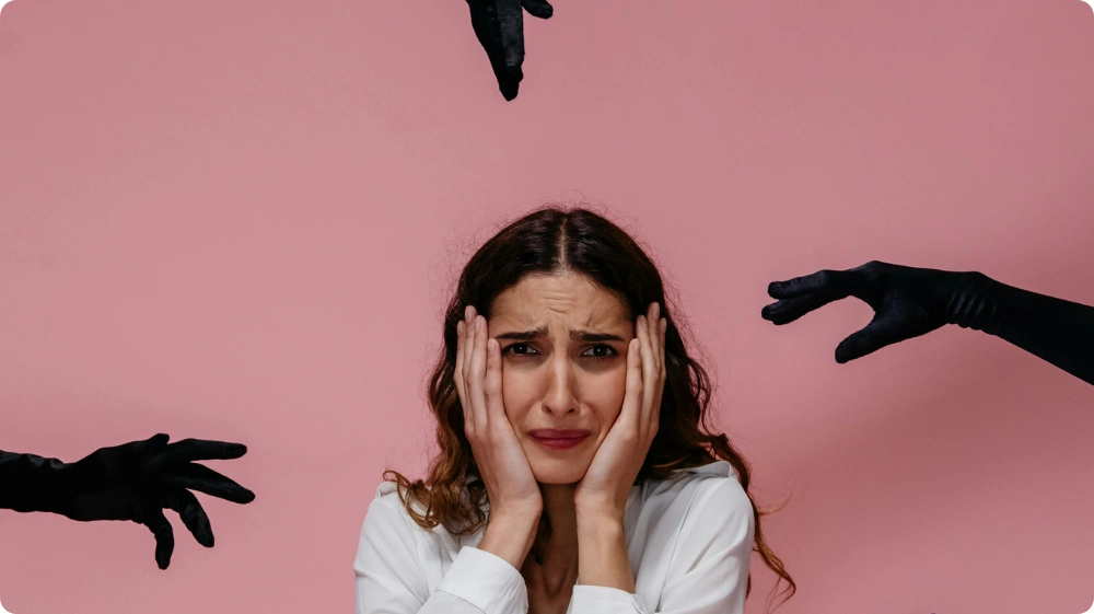 Woman feeling scared and anxious, surrounded by dark hands symbolising fear of criminals or danger