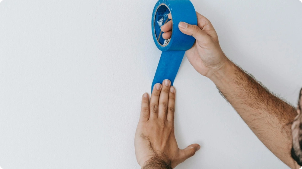 Decorator applying masking tape during wall preparation