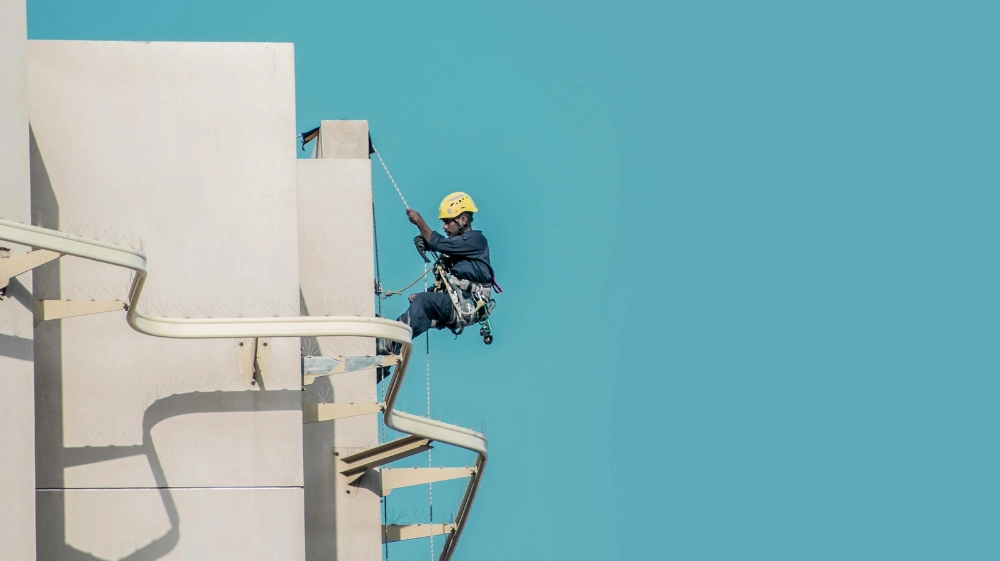 Worker wearing safety harness and helmet following UK Working at Height Regulations on a construction site 